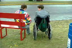 two people talking at a bench, one in wheelchair