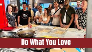 A group of people around a kitchen during a cooking class. The picture links to our Do What You Love fundraising page.