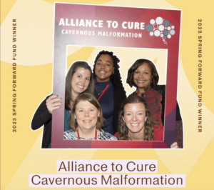 Five Alliance to Cure Cavernous Malformation staff members standing together, holding and looking through a frame with the Alliance to Cure logo.