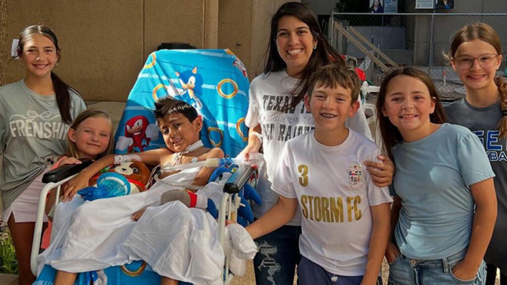 boy in a hospital bed surrounded by other children and his mother.