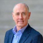 Headshot of older man wearing blue shirt and sport coat